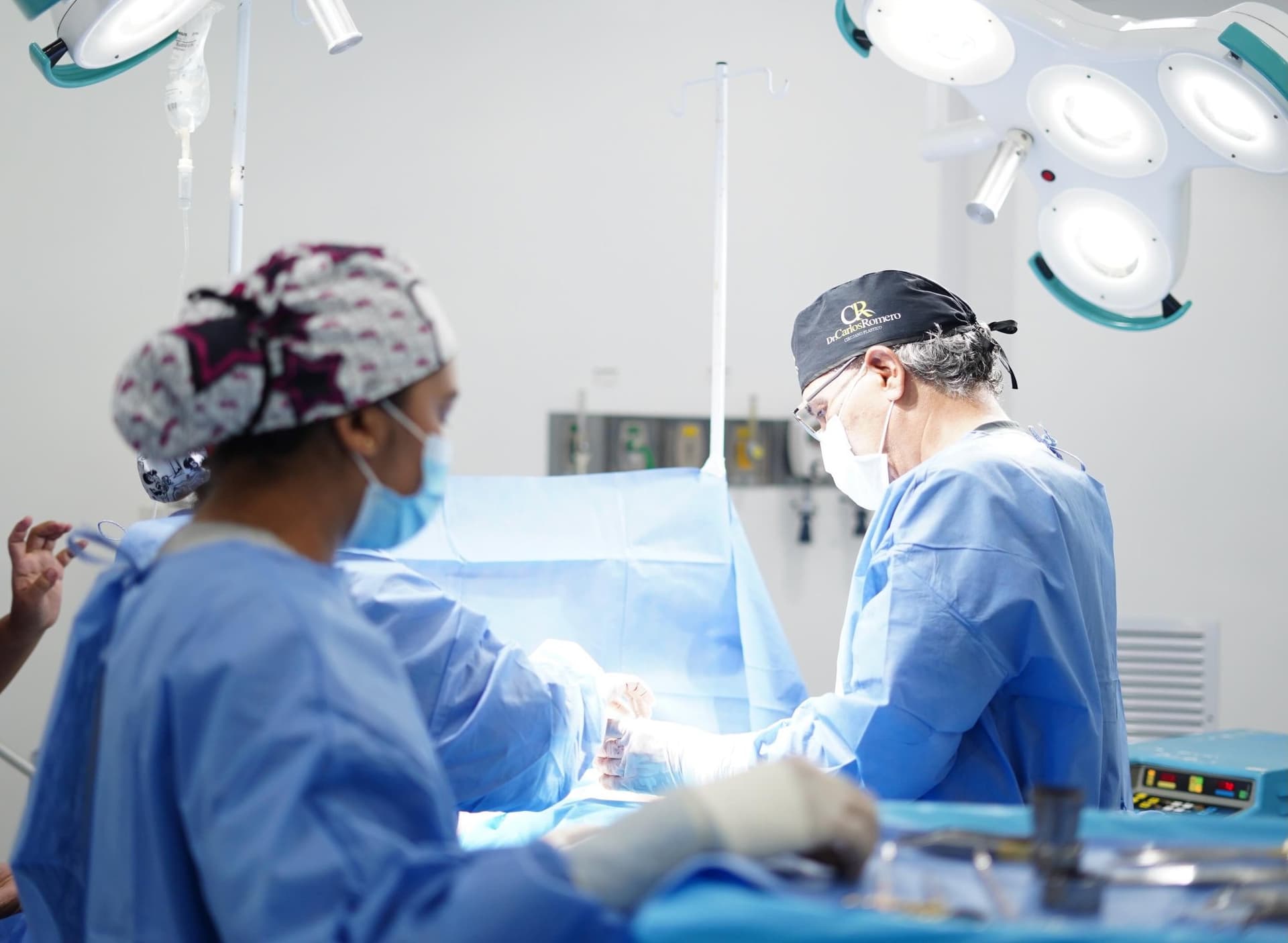 Cirujanos de la clínica operando bajo las lámparas del quirófano