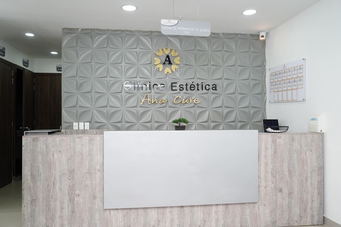 Recepción de la Clínica Estética Ana Cure con el logo dorado en la pared